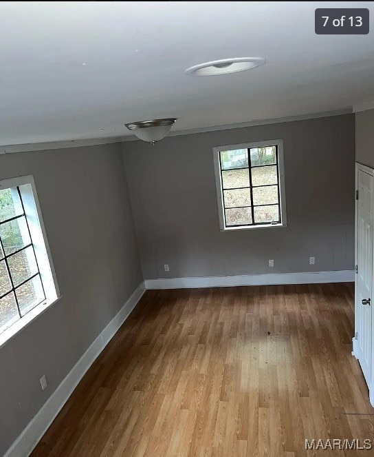 empty room with hardwood / wood-style flooring and ornamental molding