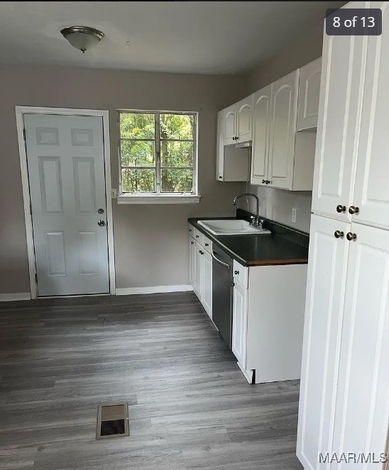 kitchen with white cabinets, stainless steel dishwasher, dark wood-type flooring, and sink