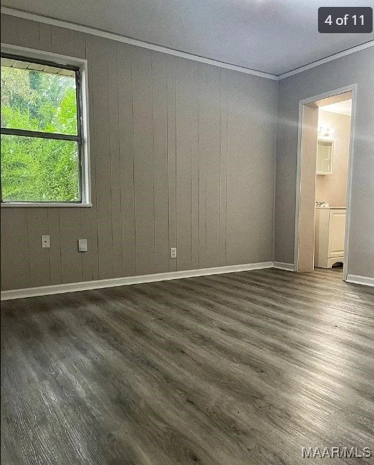 empty room featuring ornamental molding, wood walls, and dark wood-type flooring