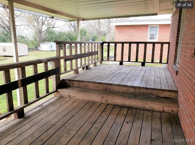 wooden deck featuring a storage shed and a yard