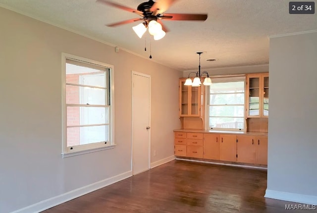 unfurnished dining area featuring ceiling fan with notable chandelier, a textured ceiling, plenty of natural light, and dark hardwood / wood-style flooring