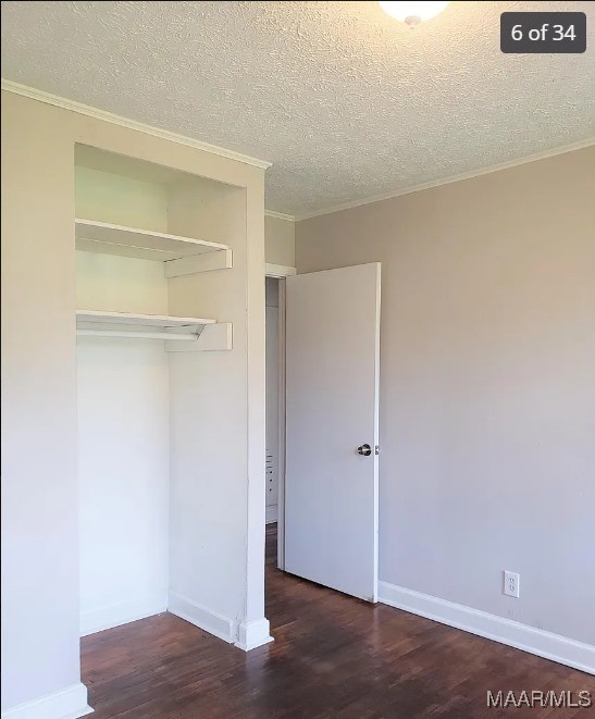 unfurnished bedroom with ornamental molding, dark hardwood / wood-style flooring, and a closet