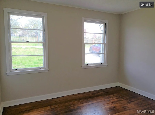 spare room with dark hardwood / wood-style floors, plenty of natural light, and crown molding