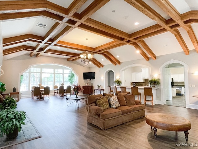 living room with hardwood / wood-style floors, an inviting chandelier, and lofted ceiling with beams