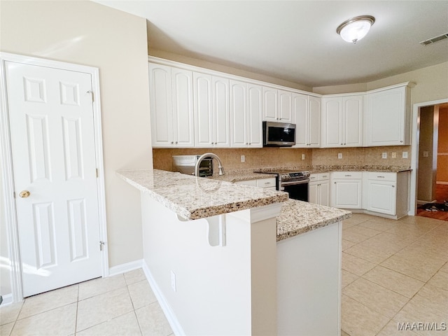 kitchen with tasteful backsplash, light stone counters, stainless steel appliances, and kitchen peninsula