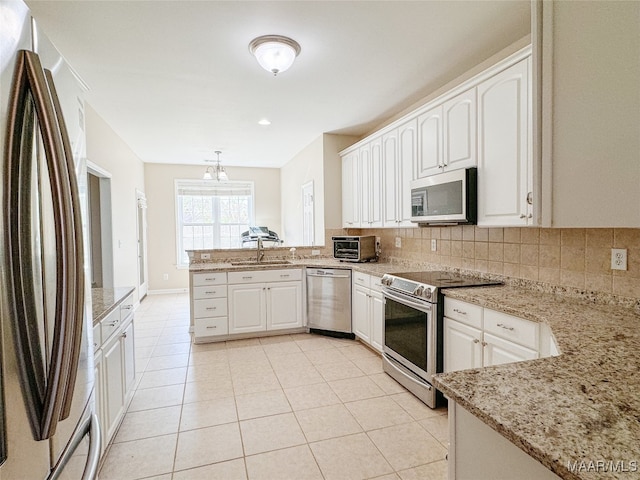 kitchen with white cabinetry, backsplash, light stone counters, kitchen peninsula, and appliances with stainless steel finishes