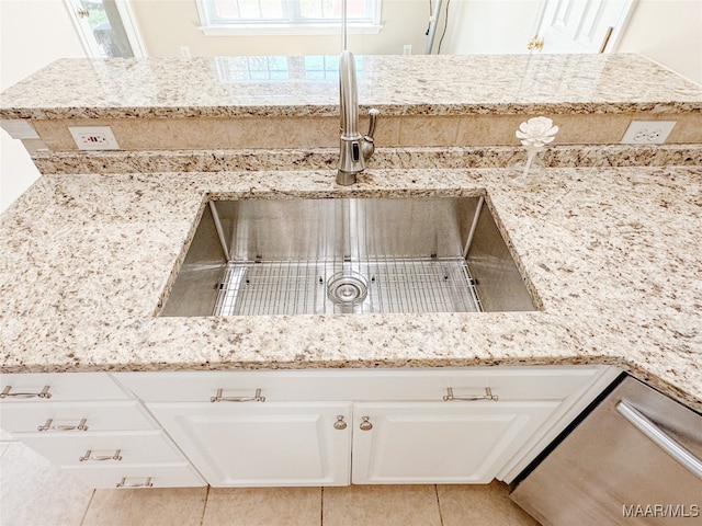 room details with light tile patterned floors, light stone counters, white cabinetry, and sink