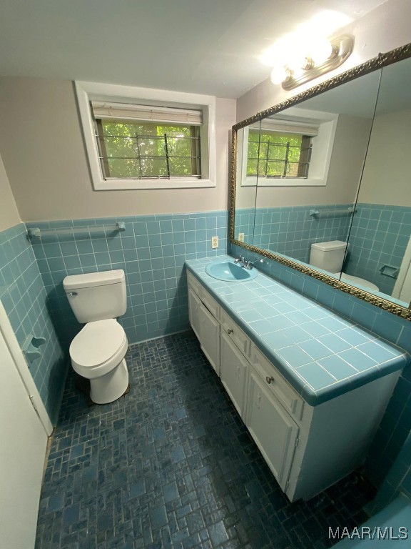 bathroom with vanity, tile walls, and toilet