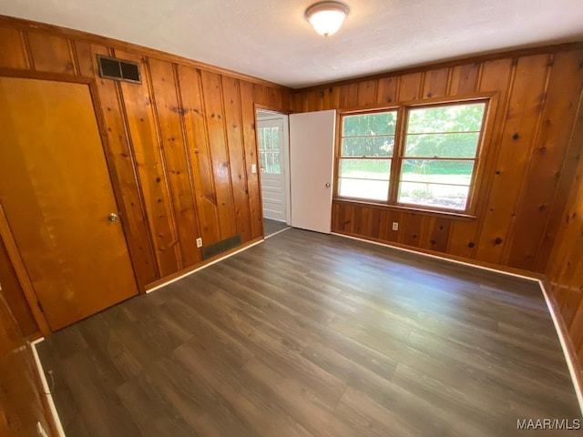 unfurnished bedroom with wood walls and dark hardwood / wood-style flooring