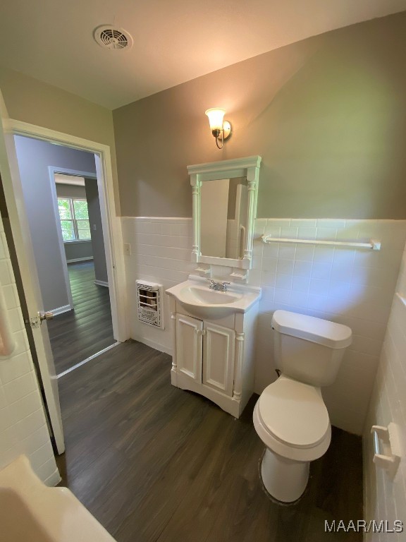 bathroom with vanity, toilet, heating unit, and hardwood / wood-style flooring