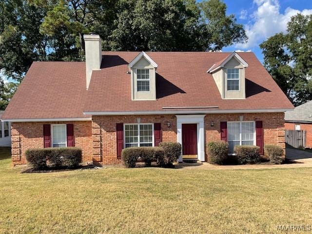 cape cod home with brick siding and a front yard