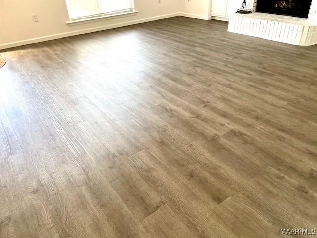 room details featuring a brick fireplace, baseboards, and wood finished floors