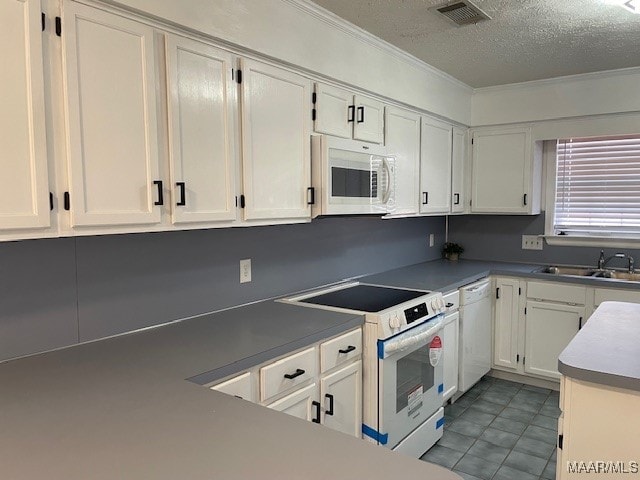 kitchen featuring white appliances, visible vents, a sink, and white cabinets