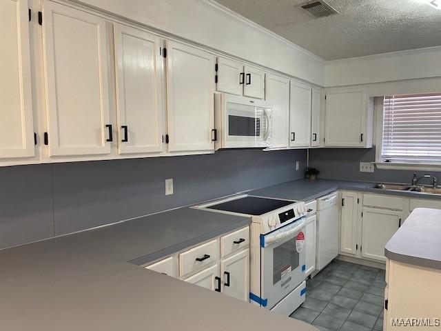 kitchen with visible vents, a sink, white appliances, a textured ceiling, and white cabinetry