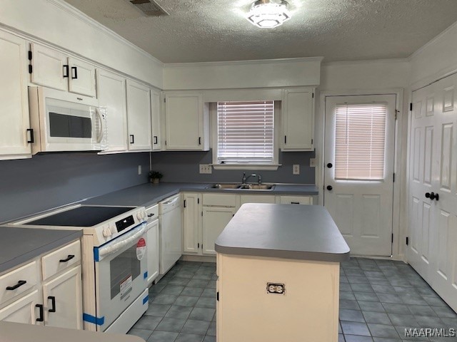 kitchen with visible vents, white cabinetry, a kitchen island, a sink, and white appliances