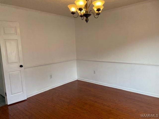 unfurnished room featuring crown molding, baseboards, wood finished floors, and a notable chandelier