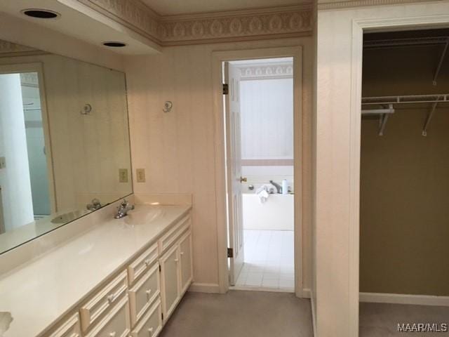 full bathroom featuring a spacious closet, baseboards, and vanity