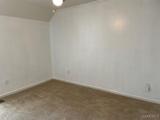 unfurnished room featuring vaulted ceiling, carpet, visible vents, and baseboards