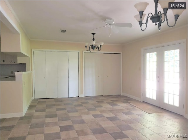 interior space with ceiling fan with notable chandelier, two closets, ornamental molding, and french doors