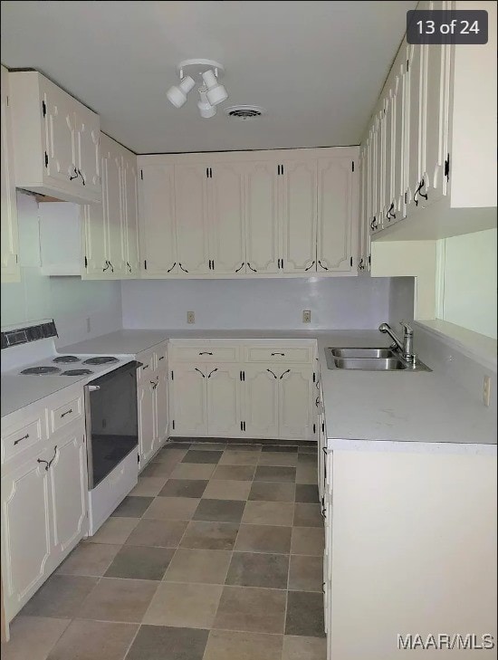 kitchen with white electric range, sink, and white cabinetry