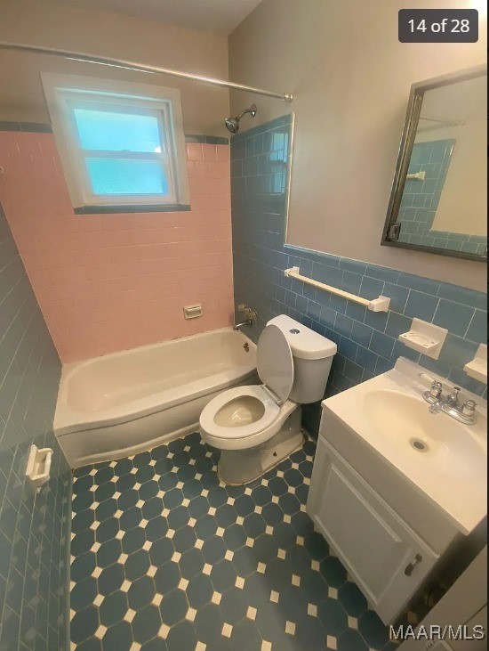 full bathroom featuring vanity, tile walls, tiled shower / bath combo, and toilet