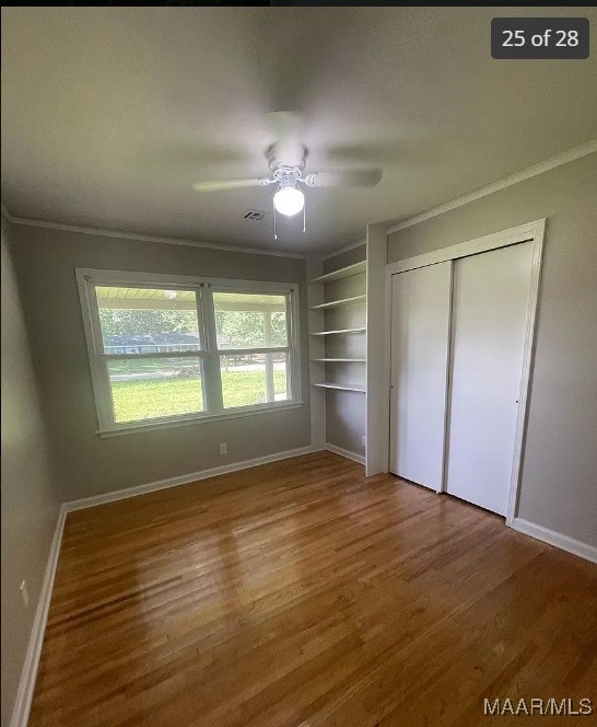 unfurnished bedroom with wood-type flooring, a closet, crown molding, and ceiling fan