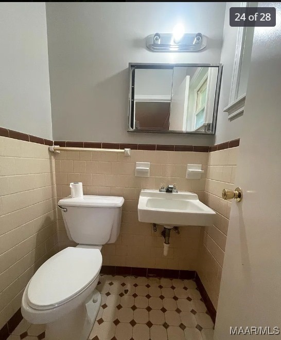 bathroom with tile walls, toilet, and sink