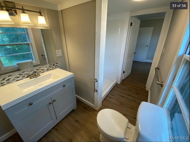 bathroom featuring hardwood / wood-style flooring, tasteful backsplash, vanity, and toilet