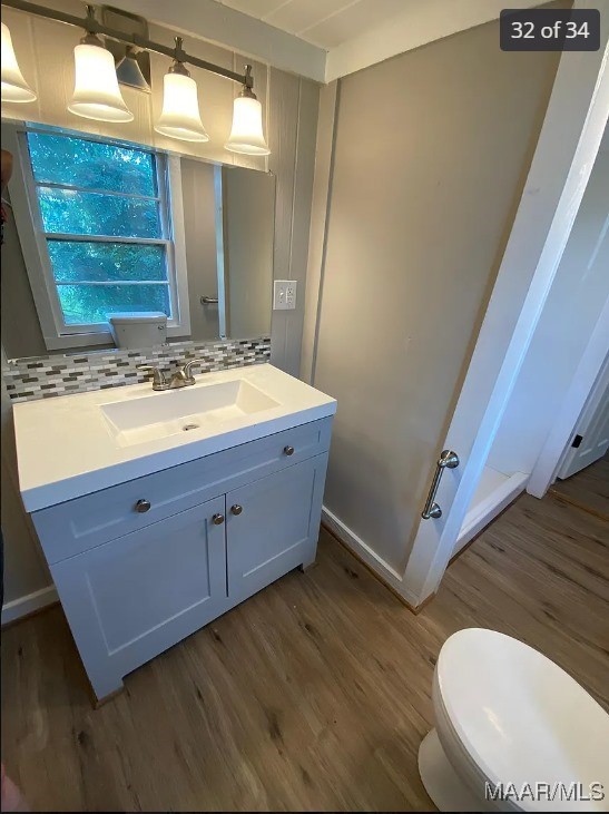 bathroom featuring backsplash, vanity, hardwood / wood-style floors, and toilet