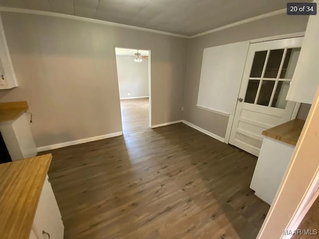 unfurnished dining area with dark wood-type flooring and crown molding