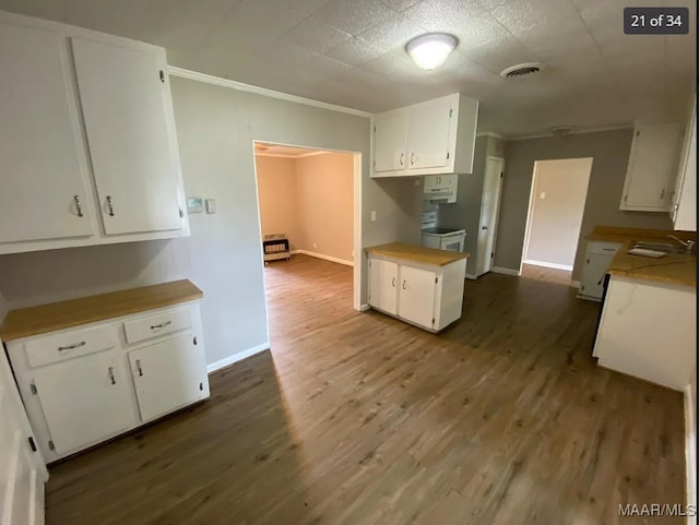 kitchen with wood-type flooring, white cabinets, crown molding, and sink