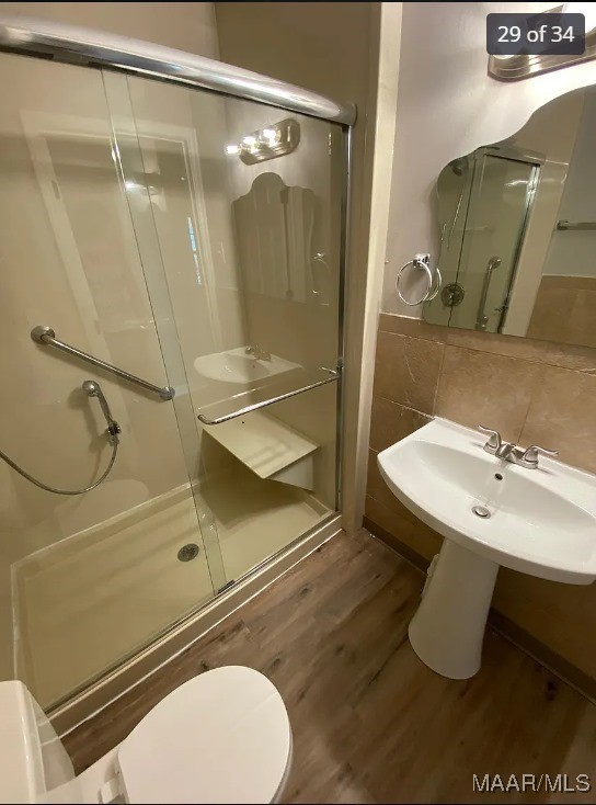 bathroom featuring hardwood / wood-style flooring, toilet, and a shower with door