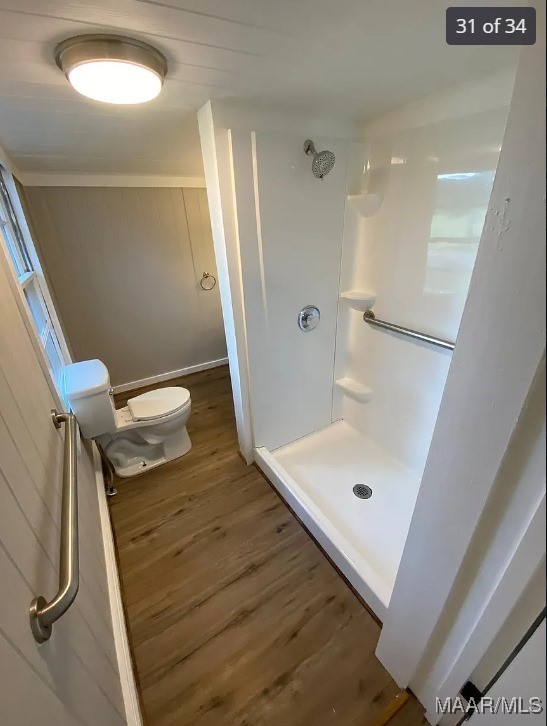 bathroom featuring a shower, hardwood / wood-style floors, and toilet