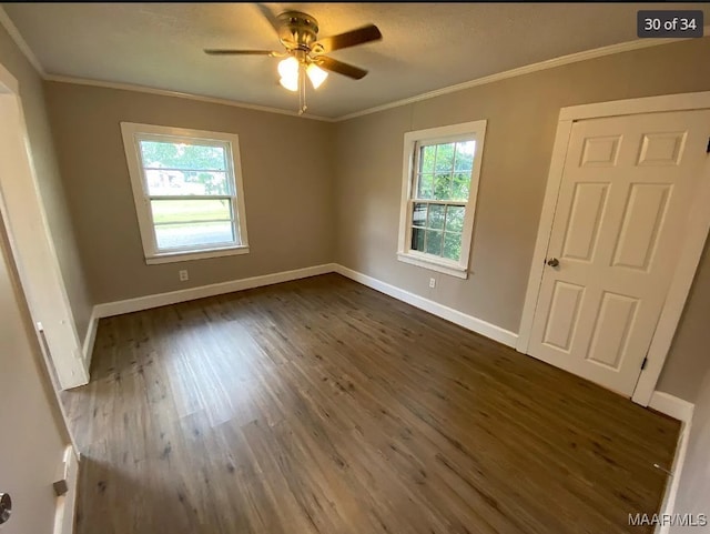 empty room with ceiling fan, crown molding, dark hardwood / wood-style flooring, and a wealth of natural light