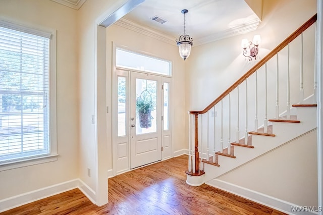 foyer with hardwood / wood-style flooring, a wealth of natural light, a chandelier, and ornamental molding