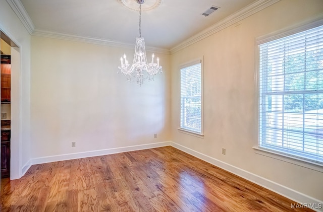 spare room featuring ornamental molding, hardwood / wood-style flooring, and an inviting chandelier