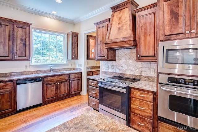 kitchen featuring light hardwood / wood-style flooring, premium range hood, stainless steel appliances, ornamental molding, and decorative backsplash