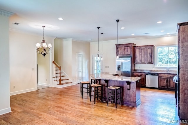 kitchen featuring light wood-type flooring, a center island, light stone counters, and stainless steel appliances