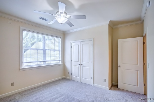 unfurnished bedroom featuring light carpet, ornamental molding, ceiling fan, and a closet