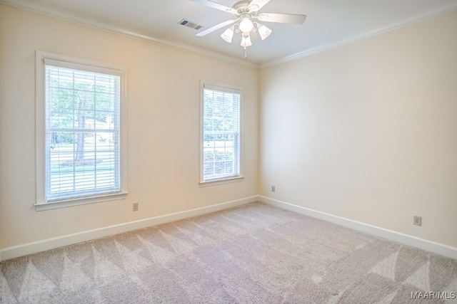 carpeted empty room featuring ceiling fan, a wealth of natural light, and ornamental molding