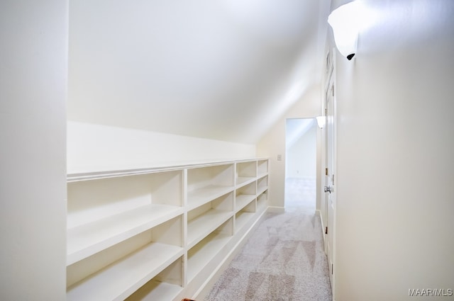 walk in closet featuring light carpet and lofted ceiling