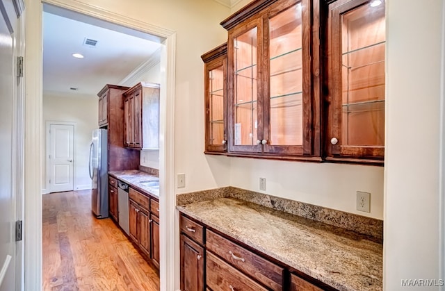 kitchen with ornamental molding, light wood-type flooring, light stone countertops, and appliances with stainless steel finishes