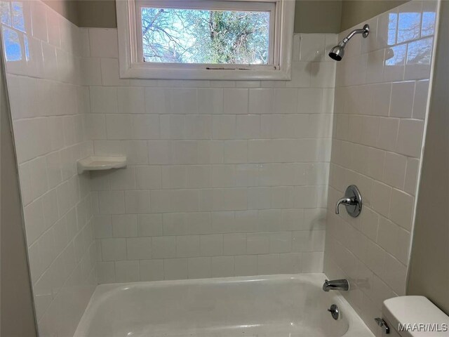 bathroom with tiled shower / bath combo and toilet