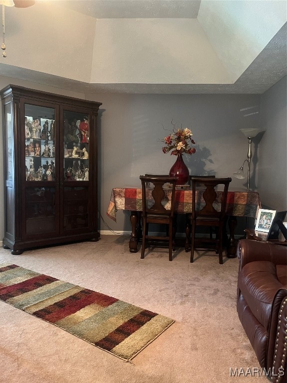 carpeted dining room with vaulted ceiling