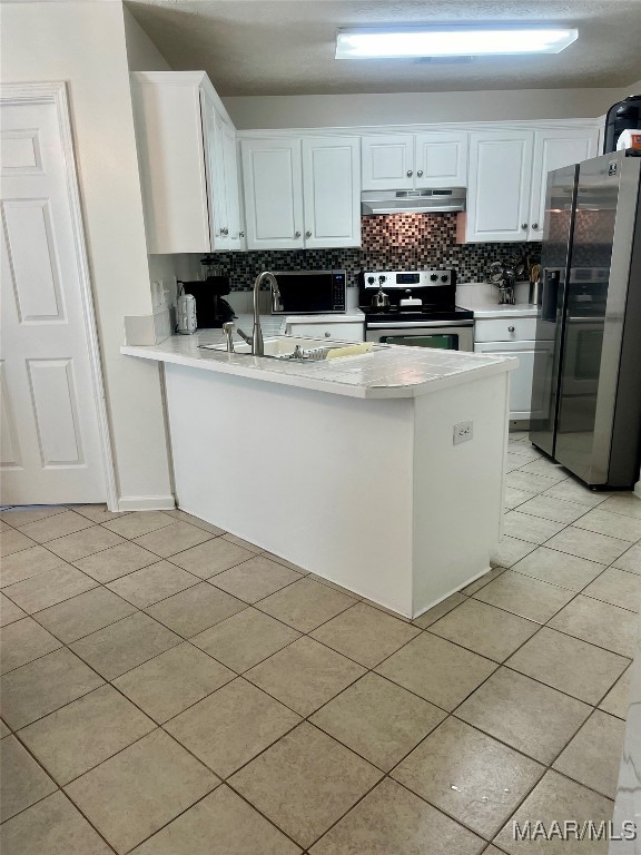 kitchen with stainless steel appliances, kitchen peninsula, and white cabinets