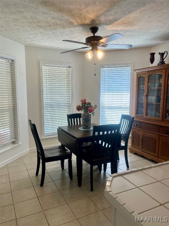 tiled dining area with a textured ceiling and ceiling fan