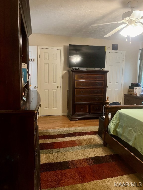 bedroom featuring ceiling fan, hardwood / wood-style flooring, and a textured ceiling