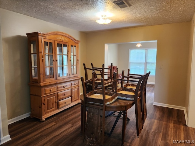 dining room with dark wood-type flooring and a textured ceiling