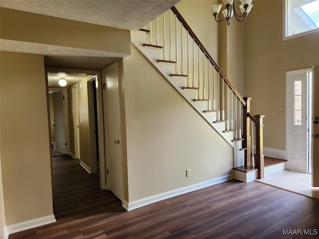 stairs featuring a textured ceiling, hardwood / wood-style flooring, and an inviting chandelier