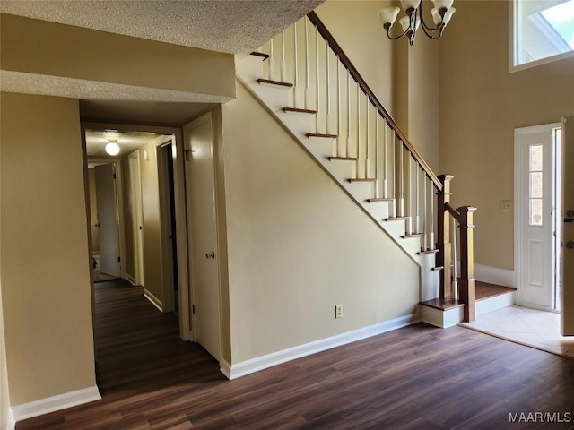 foyer entrance featuring a chandelier, stairs, baseboards, and dark wood-style flooring